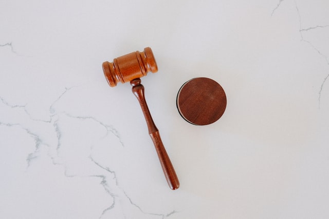 A brown wooden gavel and block against a white marble background