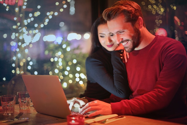 Man and woman looking at laptop with lights in the background