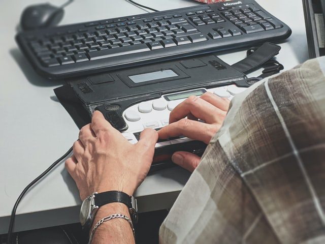 A man using a Braille display that is attached to a computer